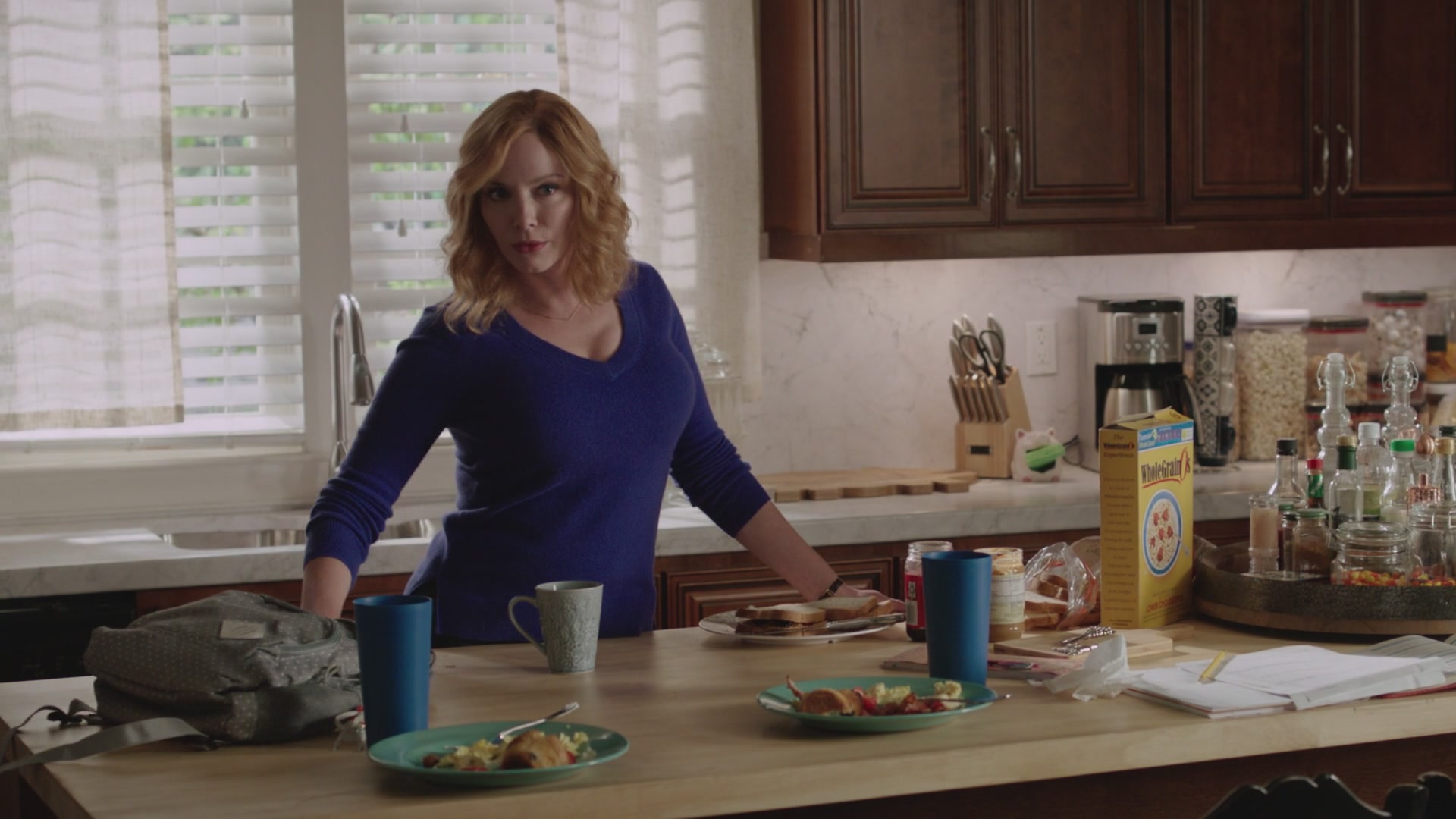 Mommy Christina in a tight blue sweater, looking up at you as she cleans up dirty plates from your kitchen counter.