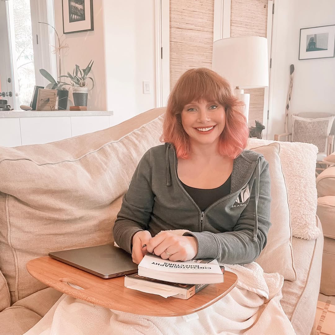 Mommy Bryce lying sideways on the couch, wrapped in a blanket as she sits up and smiles at you.